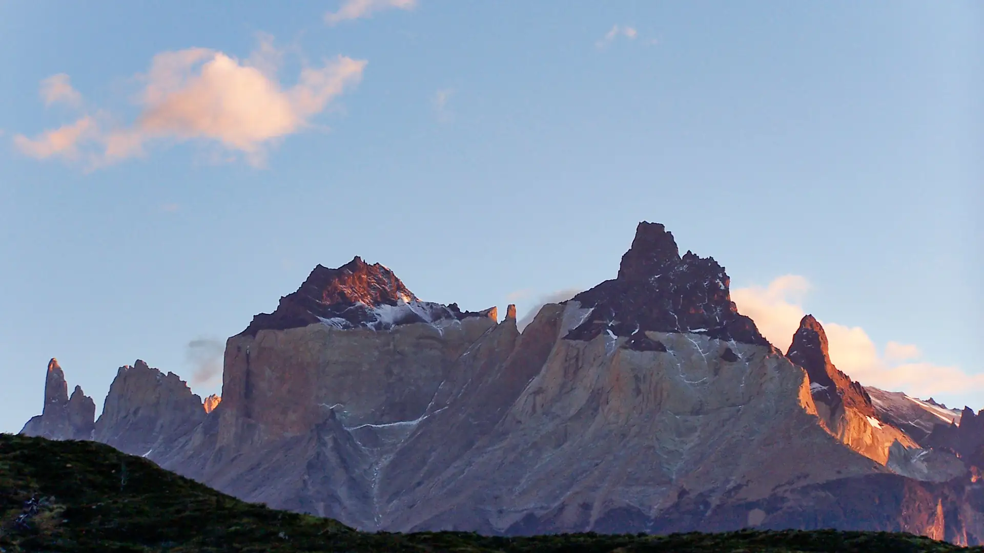 The granite Cuernos del Paine peaks catching warm sunrise light above the Patagonian steppe